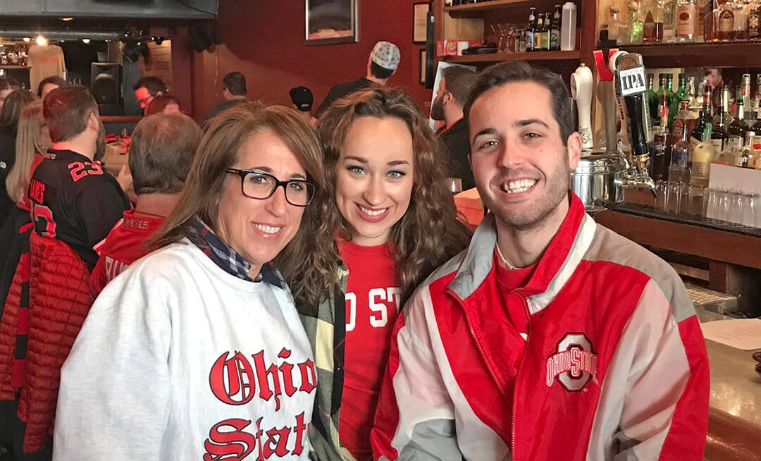 Mackenzi and family dressed in Ohio State gear watching a football game