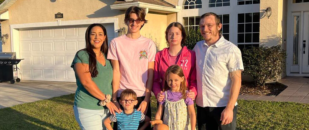 Brad standing outside with his wife and family of four