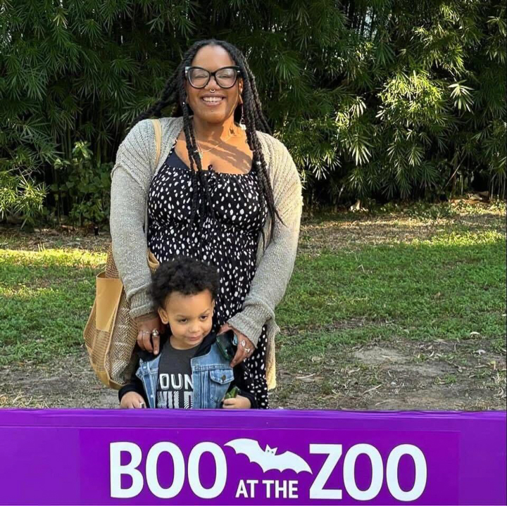 Ashley smiling with her young son at a zoo event outdoors